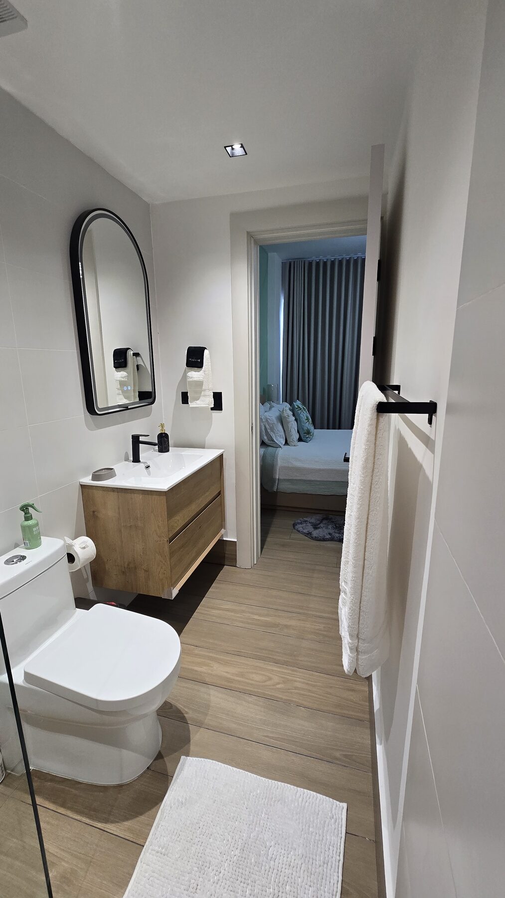 En-suite bathroom with wooden vanity opening onto the bedroom