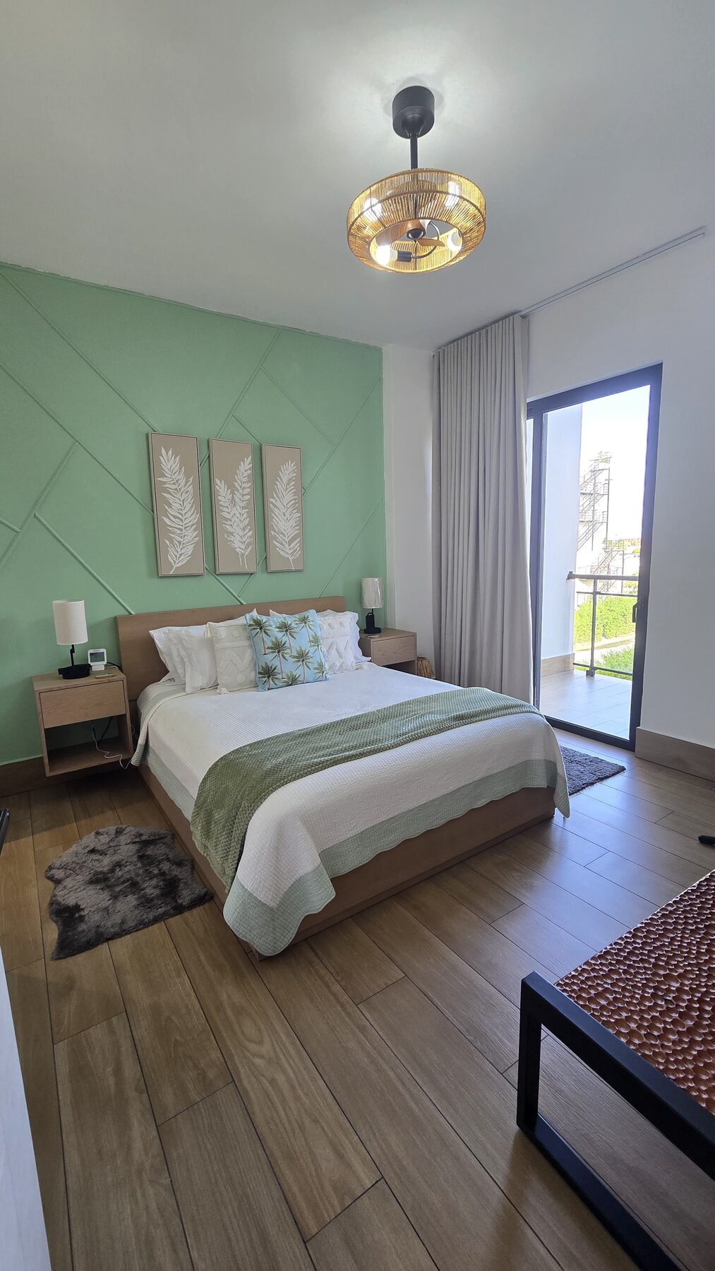 Bedroom with queen bed, green accent wall and balcony access