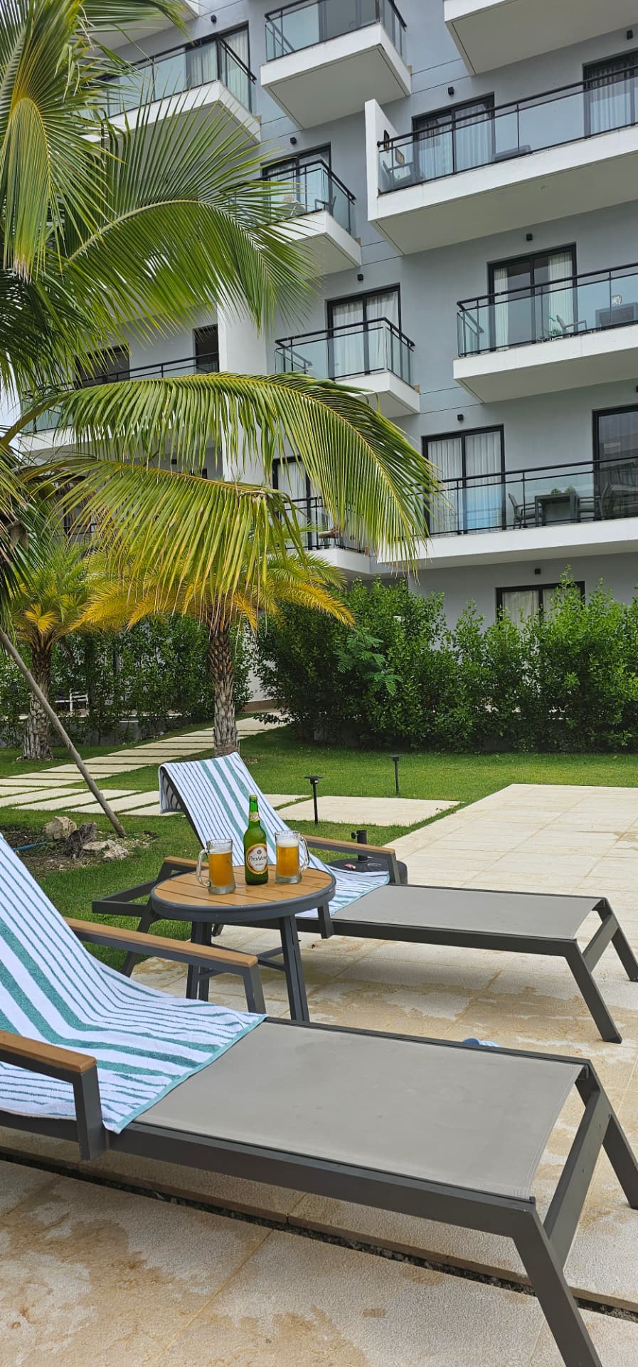 Poolside lounge chairs with palm trees and modern apartment balconies