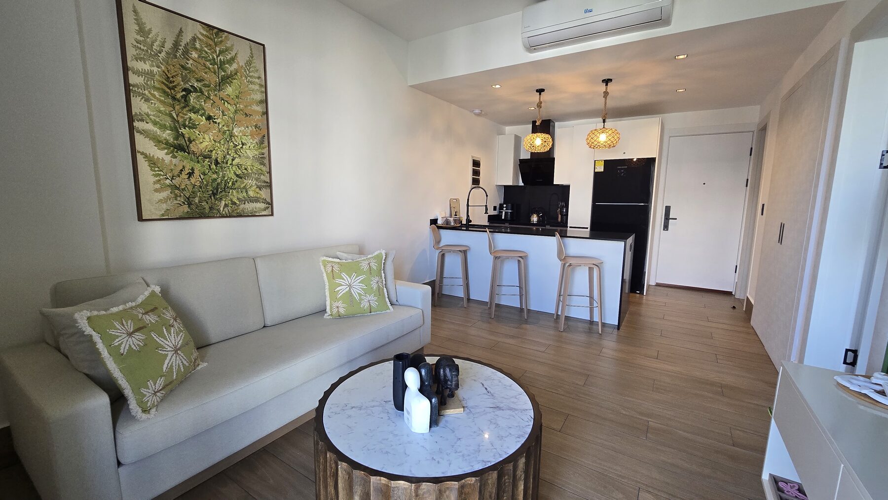 Living room sofa with tropical cushions next to the kitchen breakfast bar